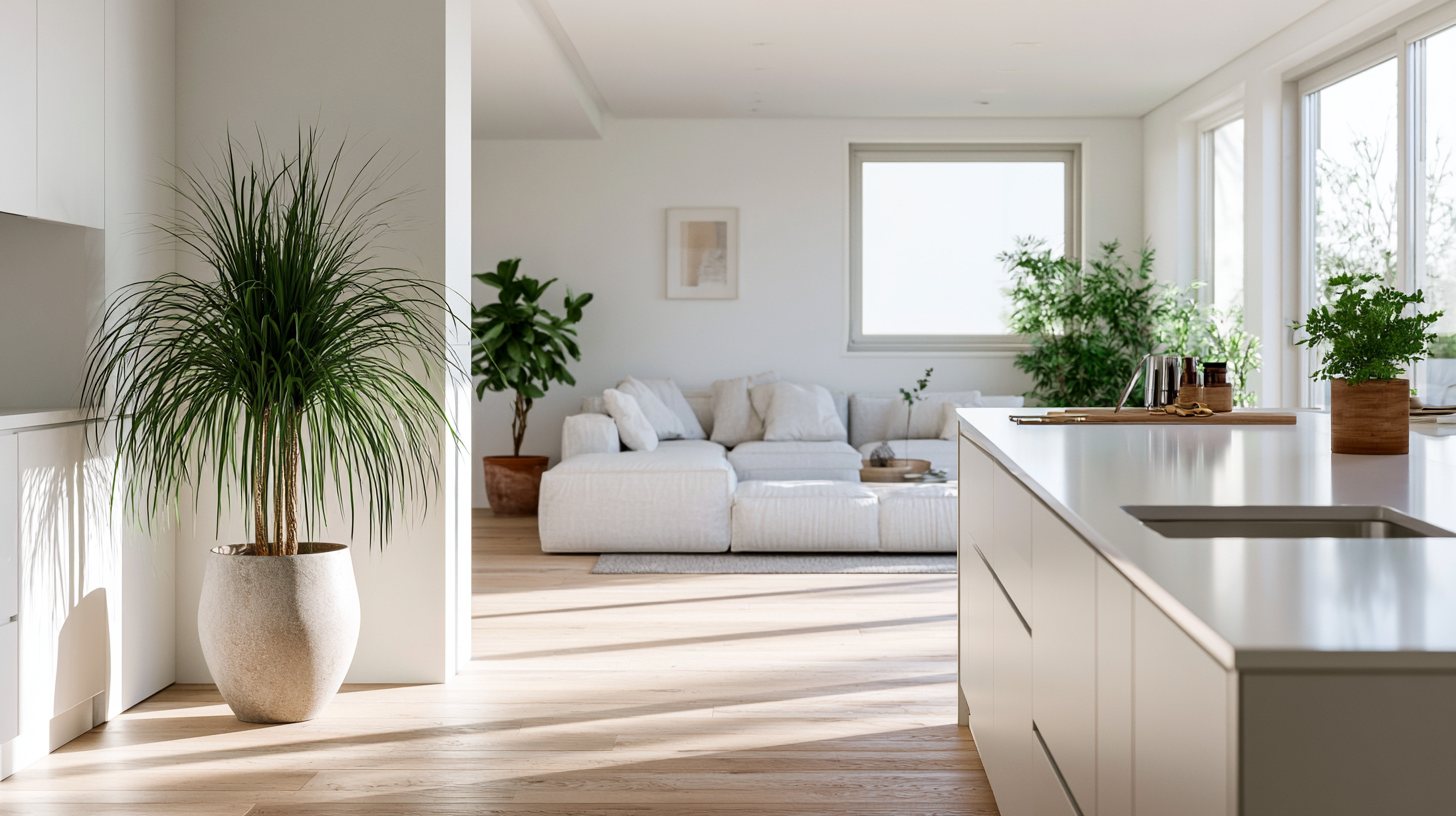 Interior luminoso de una vivienda con cocina abierta, sofá claro y plantas, bañado por luz natural cálida.